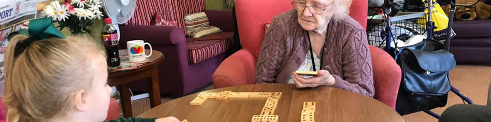 A resident playing dominoes with a young girl