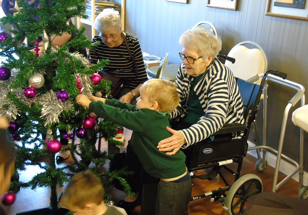 visiting children help decorate a Christmas tree