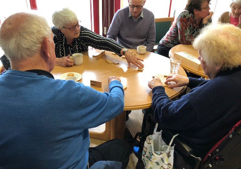 residents playing dominoes over tea and snacks