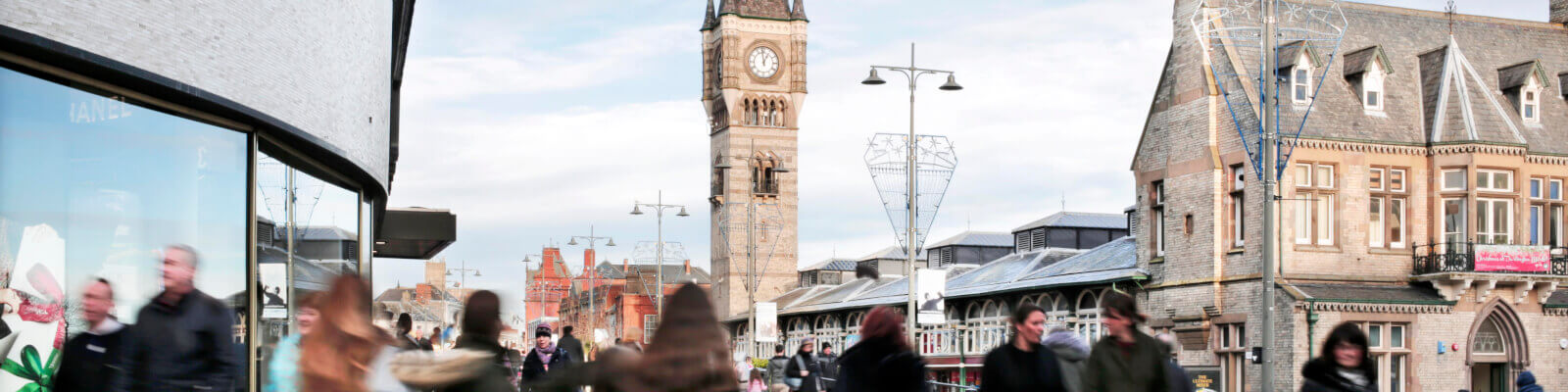 Blurred shoppers in Darlington town centre with town clock and indoor market in background