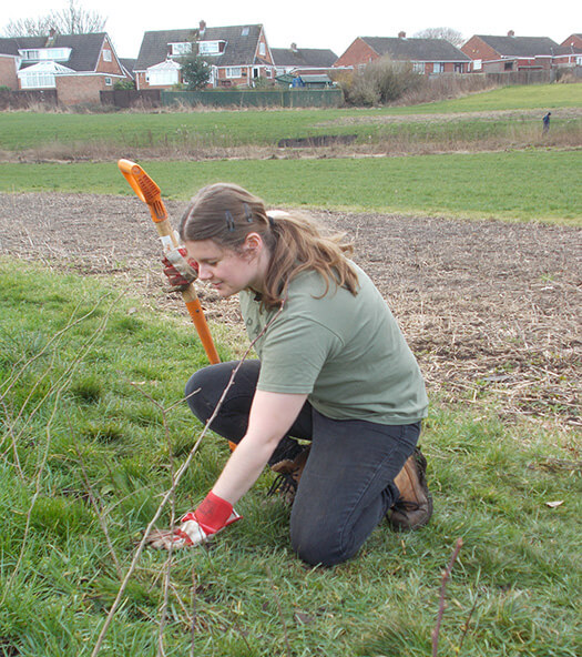 A volunteer works with a spade