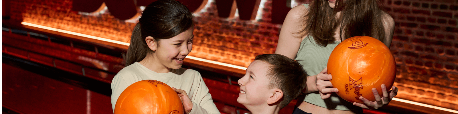 3 young children with bowling balls at DC Bowl