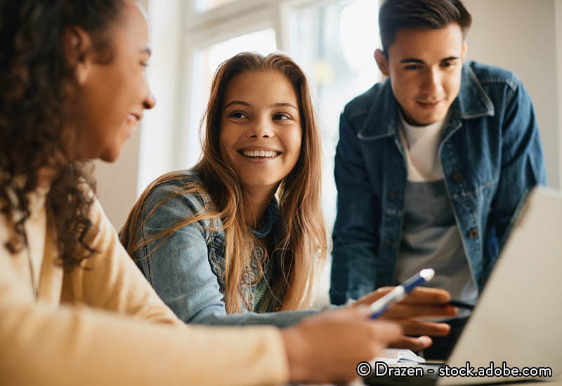 Teenagers gather round a laptop