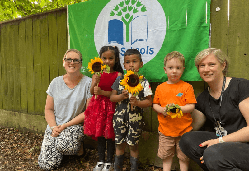 Nursery children with eco schools flag