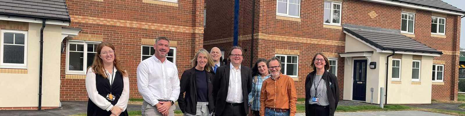 Group of people in front of newly built houses