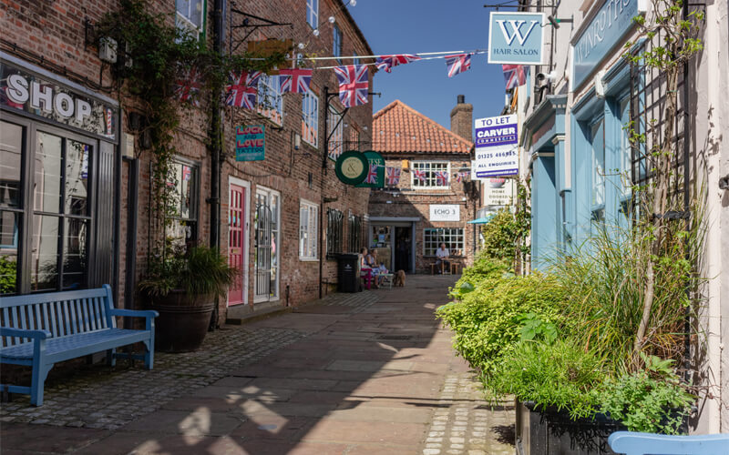 cobbled alleyway with small shops and Union Jack bunting