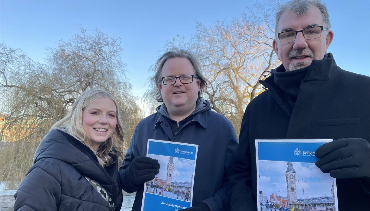 3 people stood outside holding documents