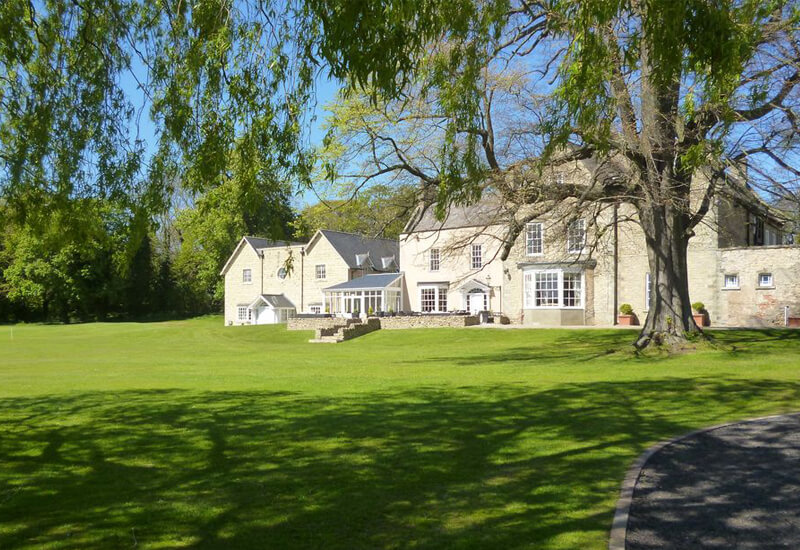 Large white manor type house set in lawned grounds