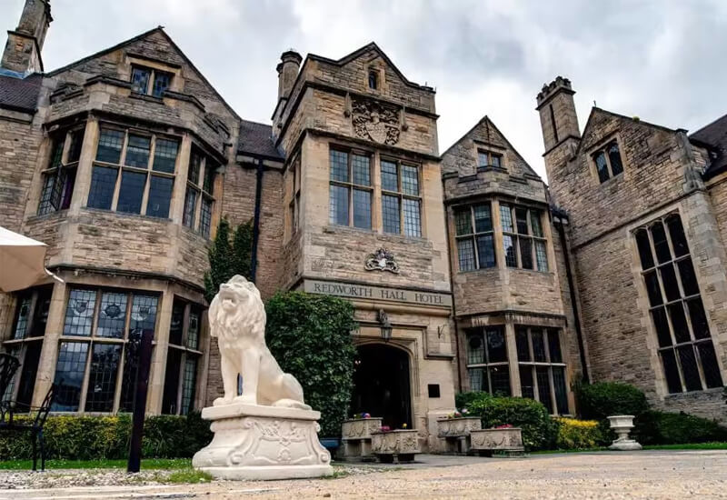 Large old style hotel with courtyard and large stone lion outside