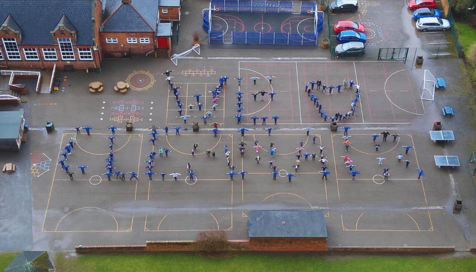 Children in playground forming the words 'we love clean air'