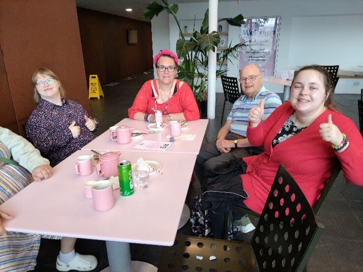 Five people sat around a table having coffee