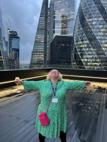 Woman stood arms stretched on roof terrace