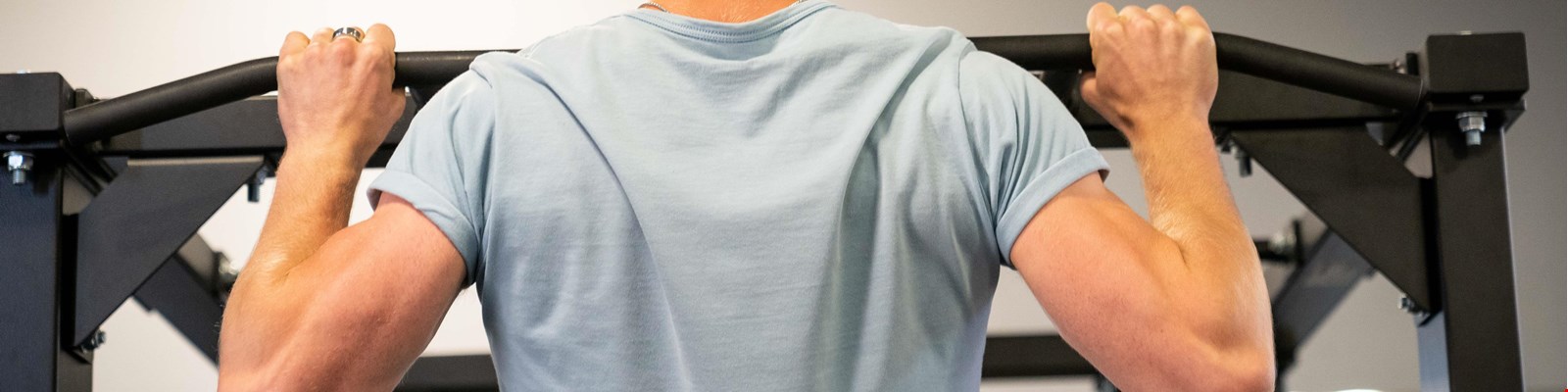 a man doing some pull ups from the back