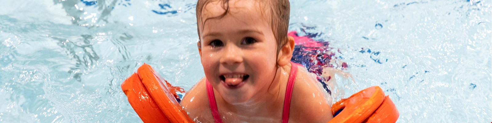 a child enjoying themselves in the pool with armbands