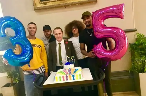 Members of the dance group Diversity celebrating the Dolphin Centre's birthday with large 3 and 5 balloons
