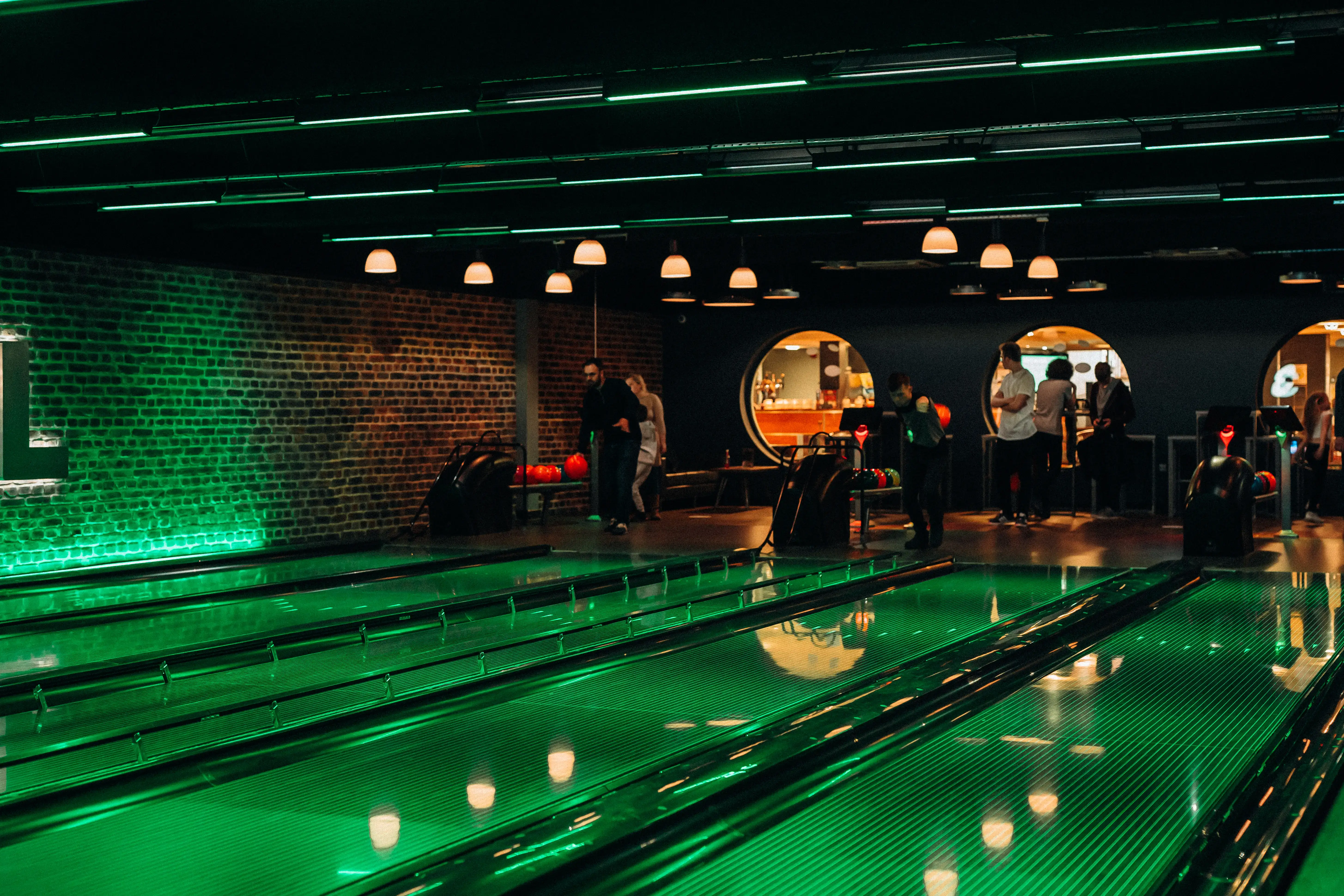 People bowling at DC bowl with green lighting